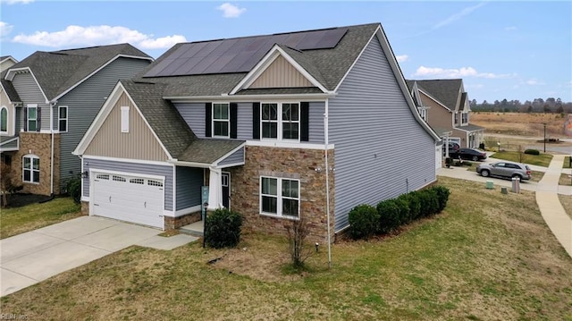 view of front of house with driveway, stone siding, roof mounted solar panels, a front yard, and a shingled roof