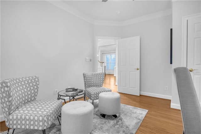 sitting room featuring ornamental molding, baseboards, and wood finished floors