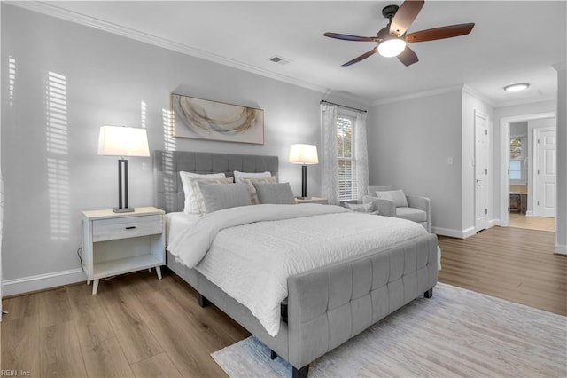 bedroom featuring wood finished floors, baseboards, visible vents, ceiling fan, and crown molding