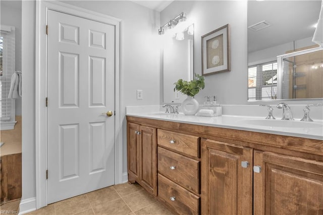 bathroom with a sink, visible vents, double vanity, and tile patterned floors