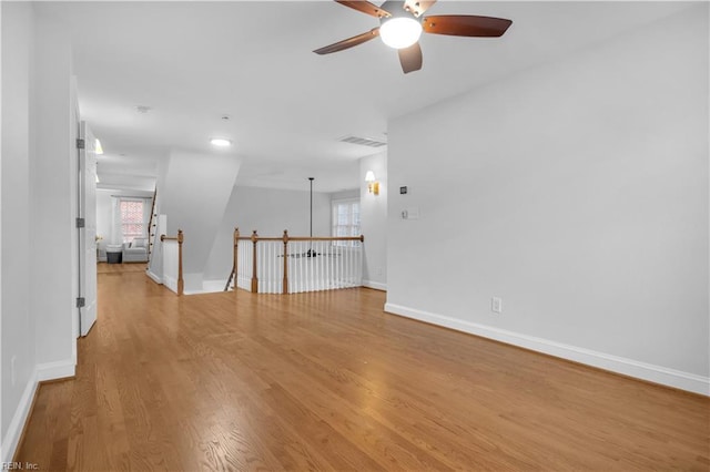 unfurnished room with light wood-type flooring, visible vents, baseboards, and a ceiling fan