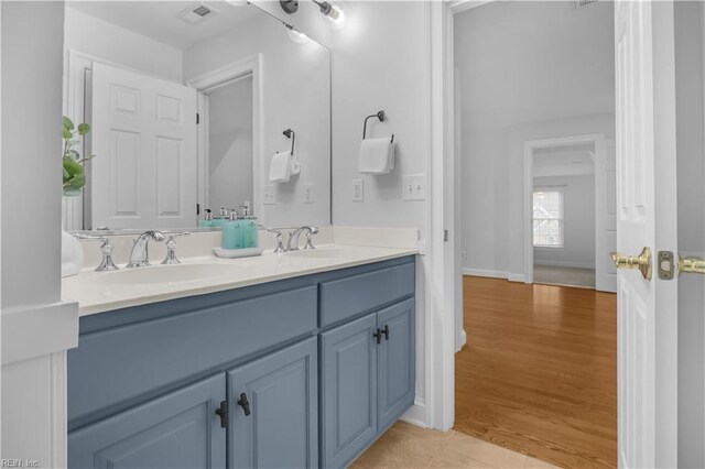 bathroom featuring a sink, visible vents, wood finished floors, and double vanity