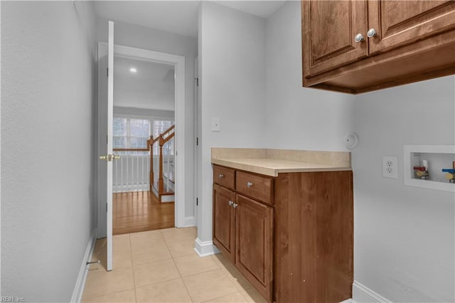 laundry area with hookup for a washing machine, light tile patterned floors, cabinet space, and baseboards