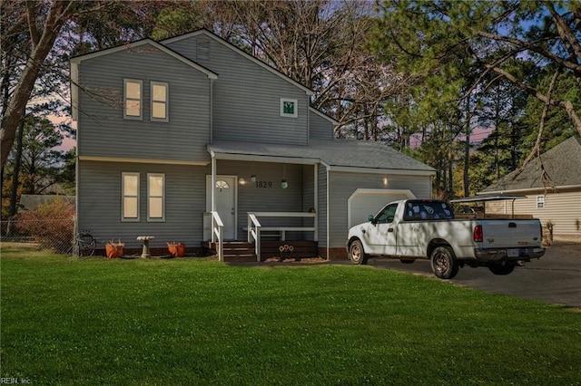 view of front of house featuring an attached garage, driveway, a front yard, and fence