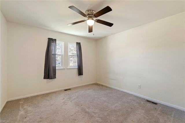 carpeted spare room featuring visible vents, baseboards, and a ceiling fan