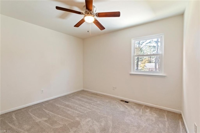 carpeted spare room featuring visible vents, ceiling fan, and baseboards