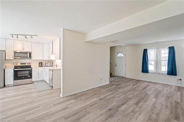 kitchen featuring baseboards, open floor plan, light countertops, appliances with stainless steel finishes, and light wood-style floors