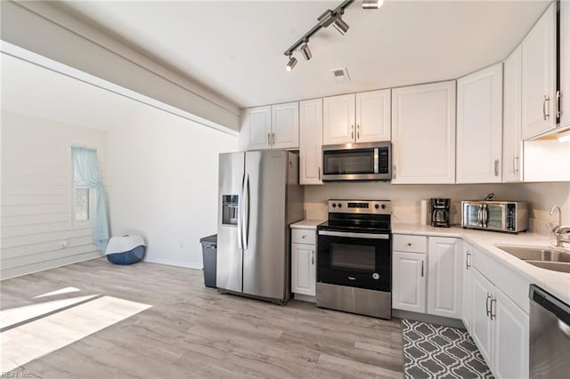 kitchen with light wood finished floors, visible vents, appliances with stainless steel finishes, and a sink