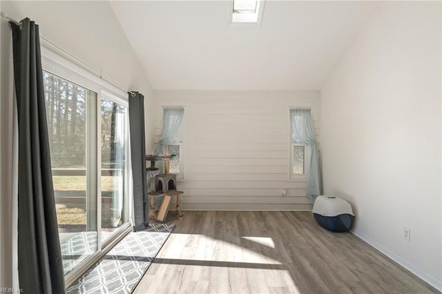 unfurnished room featuring baseboards, lofted ceiling, and wood finished floors