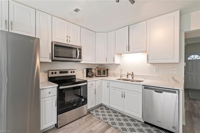 kitchen featuring a sink, visible vents, appliances with stainless steel finishes, and white cabinetry