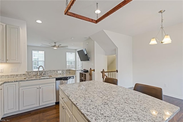 kitchen featuring dark wood finished floors, dishwasher, light stone counters, recessed lighting, and a sink