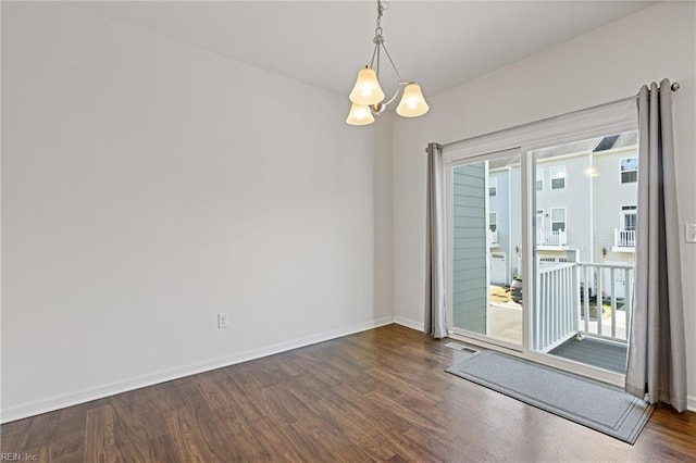 spare room with an inviting chandelier, wood finished floors, visible vents, and baseboards