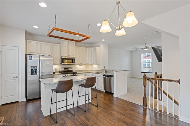 kitchen with light stone counters, recessed lighting, appliances with stainless steel finishes, a peninsula, and a ceiling fan