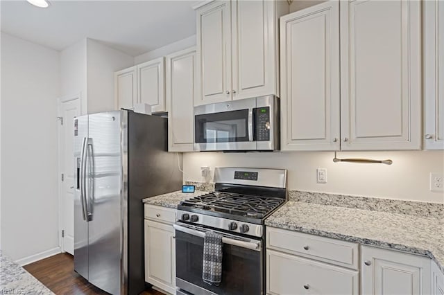 kitchen featuring white cabinetry, dark wood-type flooring, light stone countertops, and appliances with stainless steel finishes