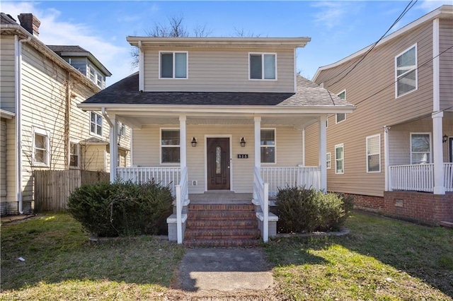 bungalow-style home with roof with shingles, a porch, and a front lawn