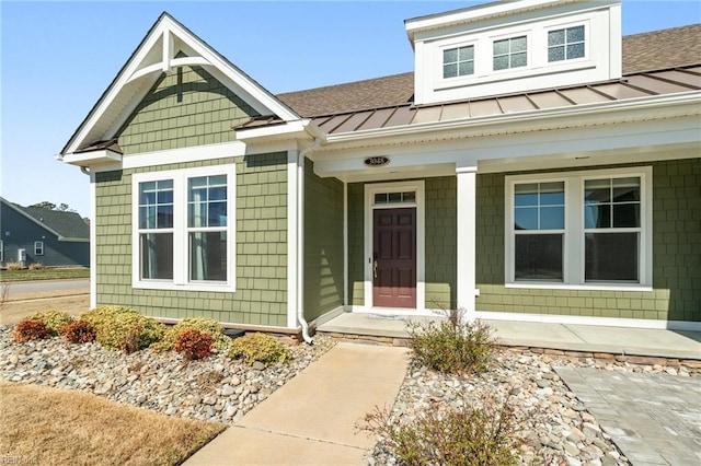 view of front of house with metal roof, covered porch, a shingled roof, and a standing seam roof