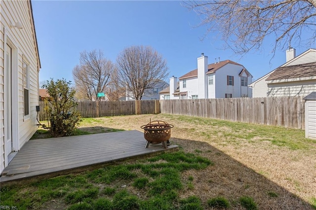 view of yard with a wooden deck, a fenced backyard, and an outdoor fire pit