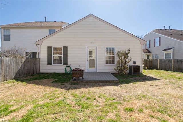 back of property with a lawn, central AC, a fenced backyard, and an outdoor fire pit