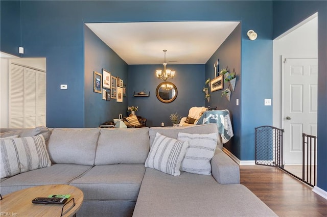 living area with baseboards, a notable chandelier, and wood finished floors