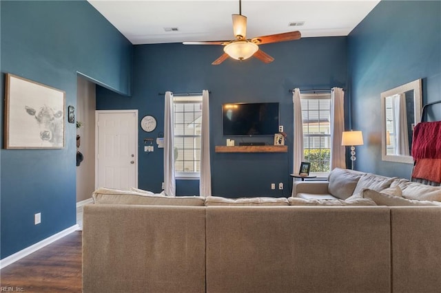 living area with dark wood finished floors, visible vents, a ceiling fan, and baseboards