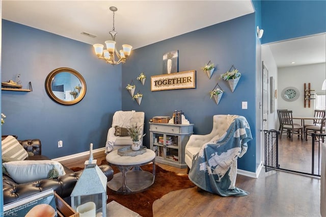 living area featuring a chandelier, visible vents, baseboards, and wood finished floors