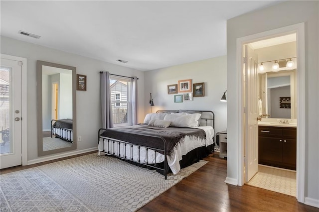 bedroom with dark wood finished floors, visible vents, baseboards, and a sink