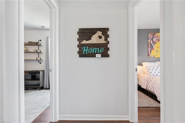 hallway featuring visible vents, baseboards, and dark wood-style flooring