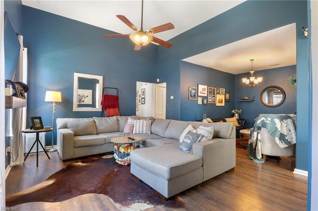 living room with ceiling fan with notable chandelier, high vaulted ceiling, baseboards, and wood finished floors