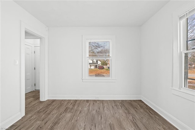 spare room with baseboards and wood finished floors