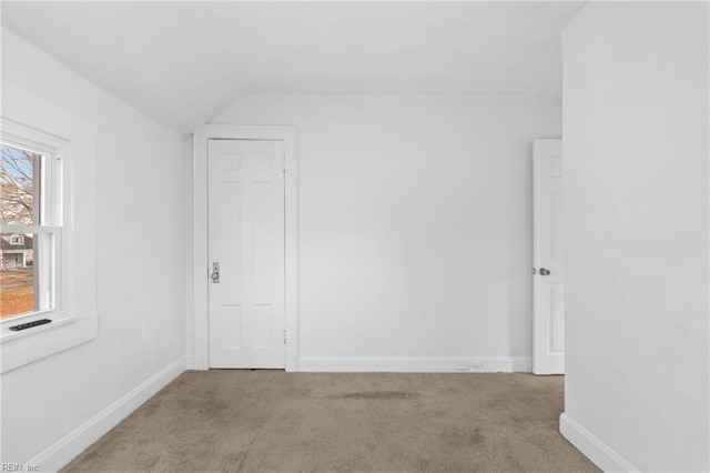 unfurnished room with vaulted ceiling, carpet flooring, and baseboards