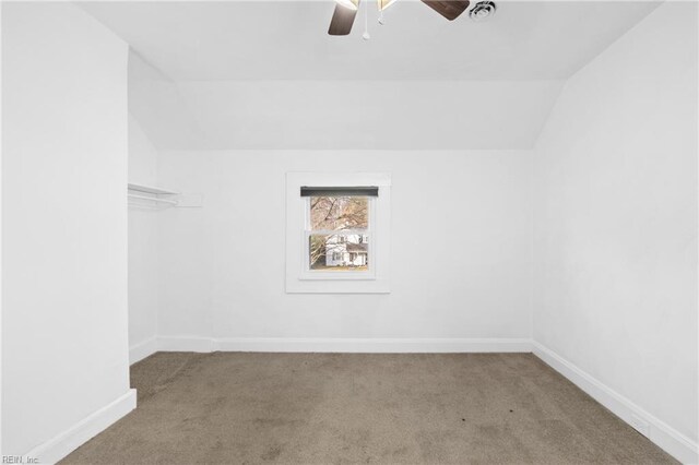 carpeted empty room with ceiling fan, baseboards, and vaulted ceiling