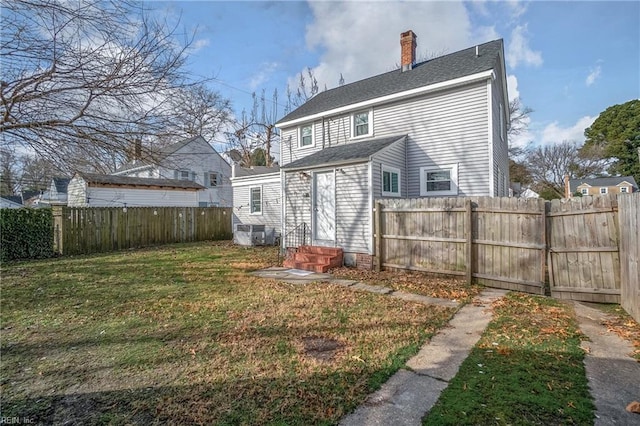 back of property featuring a shingled roof, entry steps, fence private yard, a lawn, and a chimney