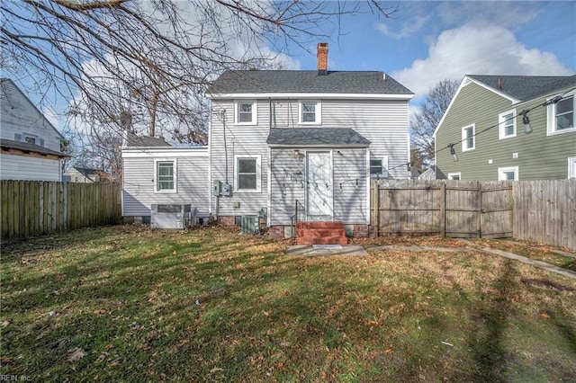 back of house with a yard, a fenced backyard, a chimney, and entry steps