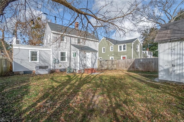 back of property with a yard, an outdoor structure, a fenced backyard, and a chimney