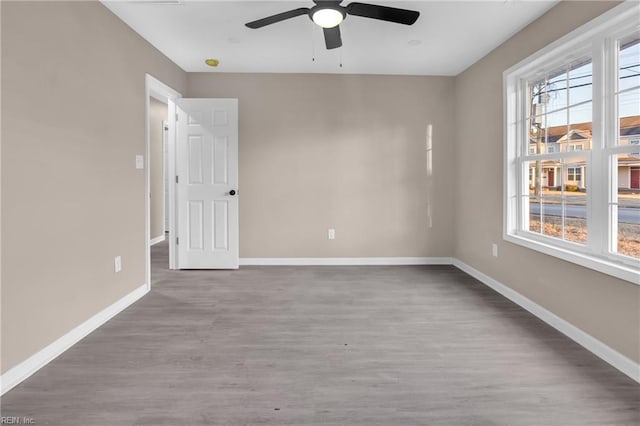 unfurnished room with a ceiling fan, wood finished floors, and baseboards