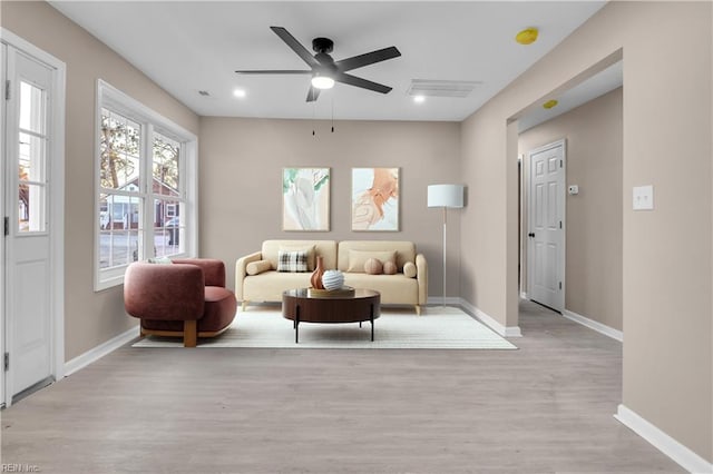 living area with visible vents, baseboards, a ceiling fan, and light wood finished floors