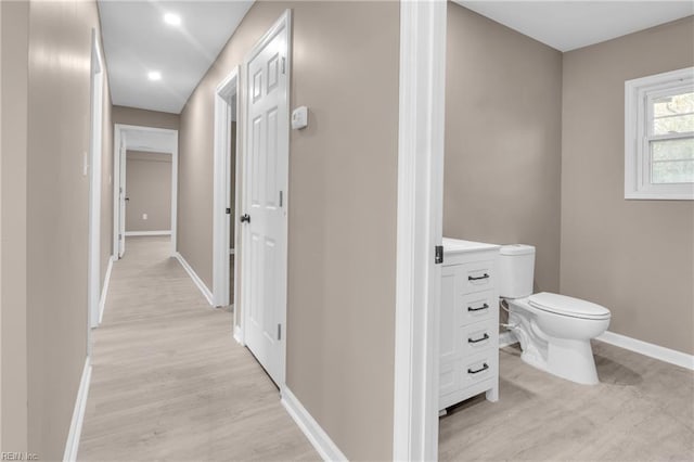 corridor with light wood-type flooring and baseboards