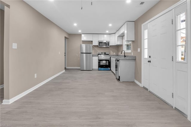 kitchen with a wealth of natural light, light wood-style flooring, white cabinets, and appliances with stainless steel finishes