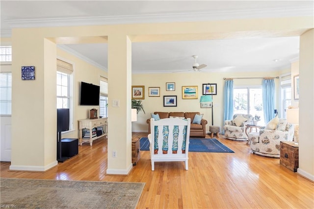 living room featuring baseboards, wood finished floors, a healthy amount of sunlight, and ornamental molding