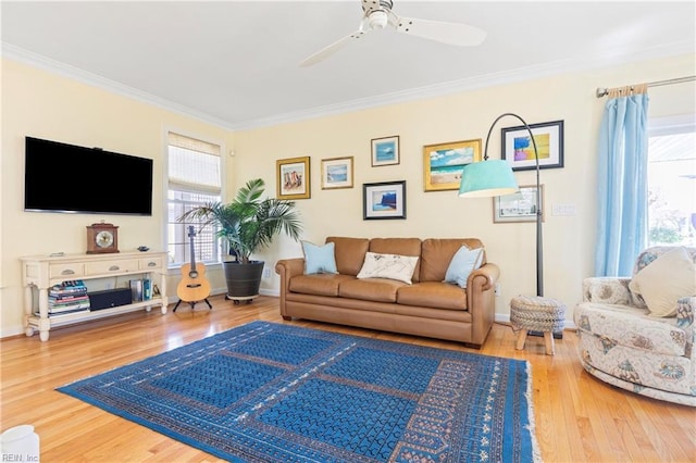 living area with crown molding, wood finished floors, a wealth of natural light, and ceiling fan