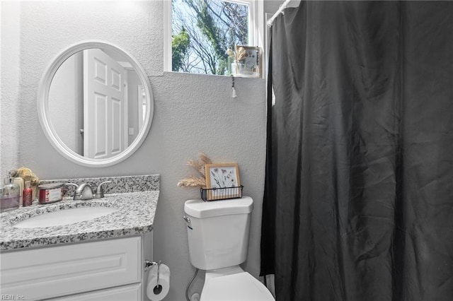 bathroom featuring toilet, vanity, a shower with shower curtain, and a textured wall