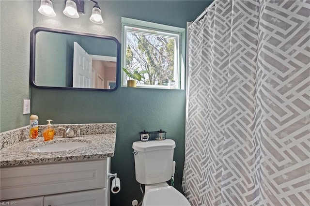 bathroom with a shower with curtain, toilet, vanity, and a textured wall