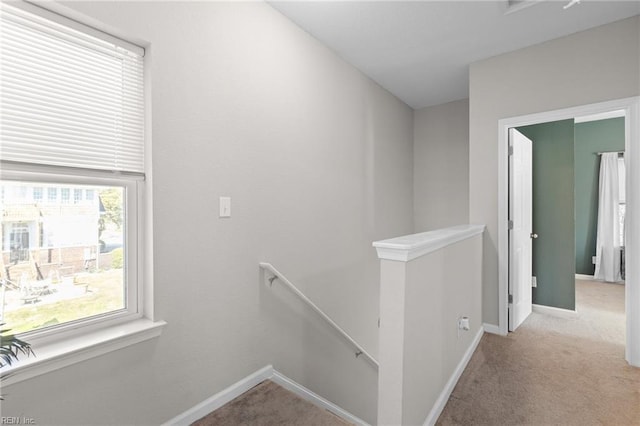 hall with baseboards, an upstairs landing, and carpet flooring