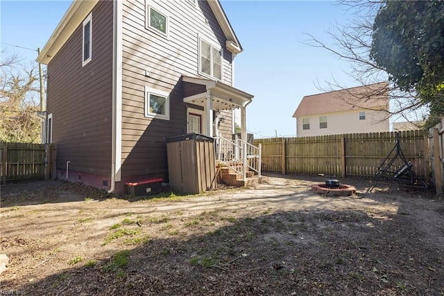 back of property with crawl space, a fenced backyard, and an outdoor fire pit