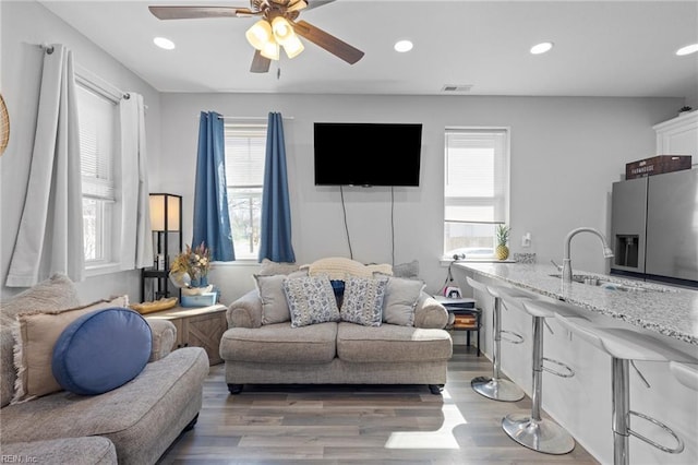 living area with a ceiling fan, light wood-style flooring, recessed lighting, and visible vents