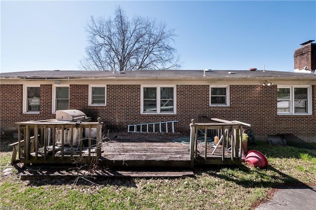 back of property featuring brick siding, a chimney, and a wooden deck