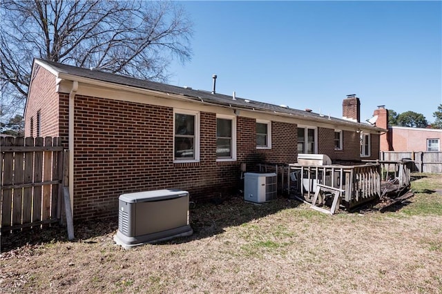 rear view of property with fence, brick siding, and a lawn