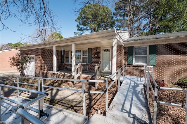 ranch-style house featuring brick siding, a fenced front yard, a porch, and a garage