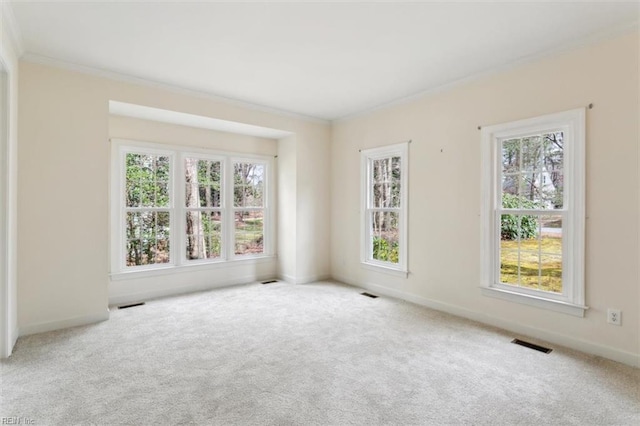 carpeted empty room with visible vents, baseboards, a healthy amount of sunlight, and crown molding