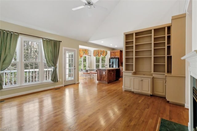 unfurnished living room featuring a ceiling fan, visible vents, high vaulted ceiling, light wood-style flooring, and a fireplace with flush hearth